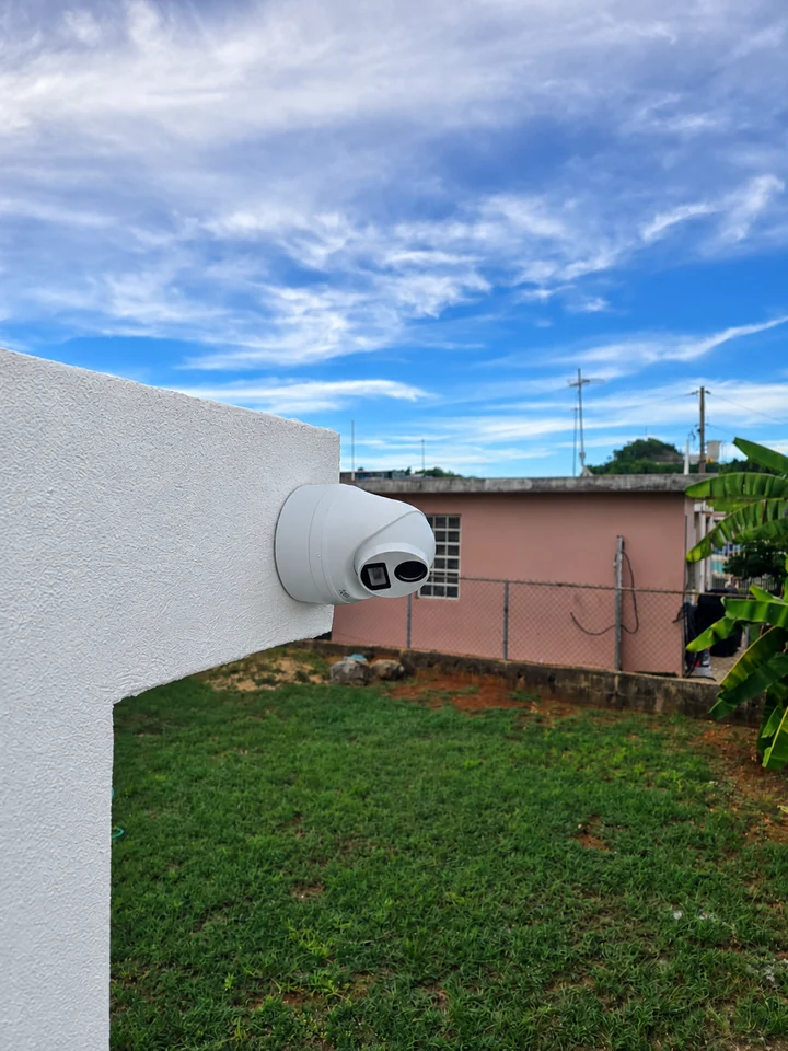 Primer plano de una cámara blanca y su base fijadas a un muro exterior blanco.